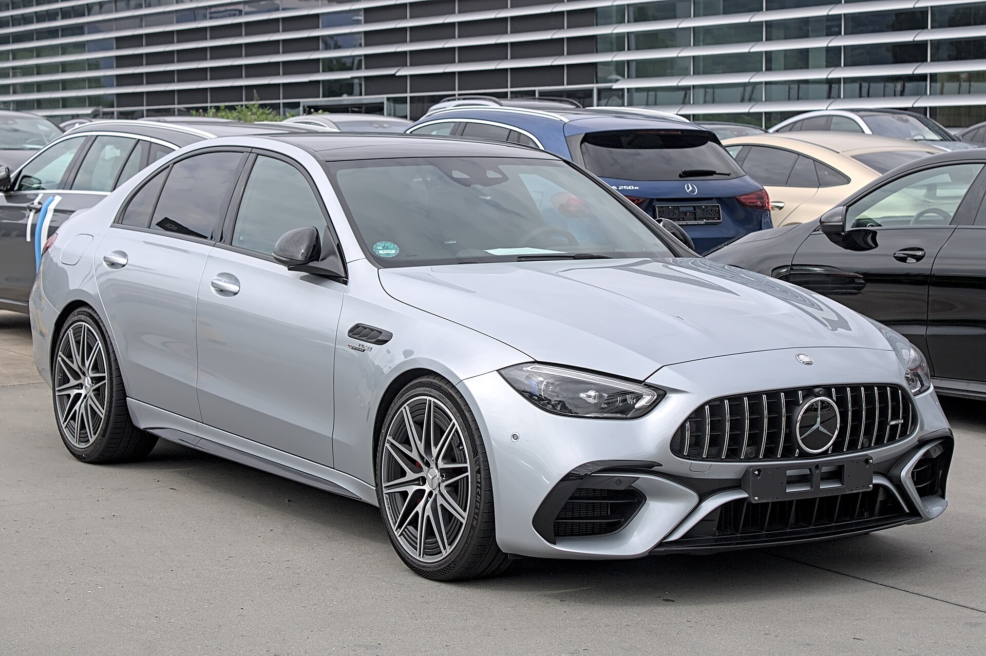 Silver Mercedes-Benz C-Class (W206) front three-quarter view outside a glass building