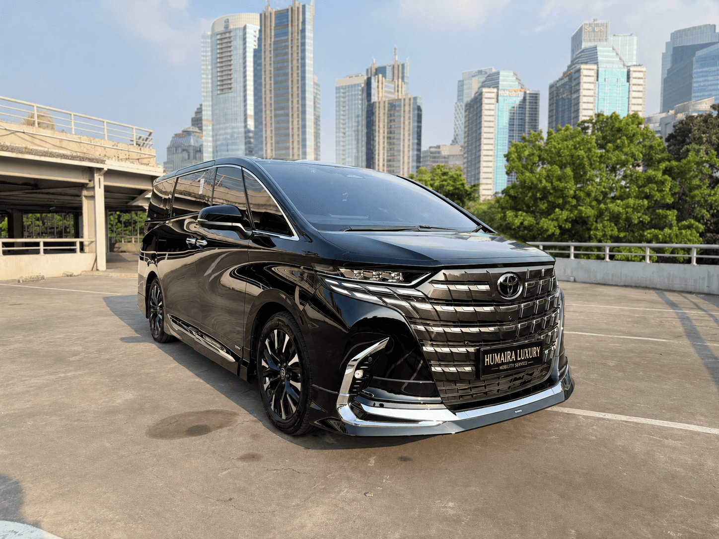 Black Toyota Alphard Hybrid (AH40) front three-quarter view against a stone wall
